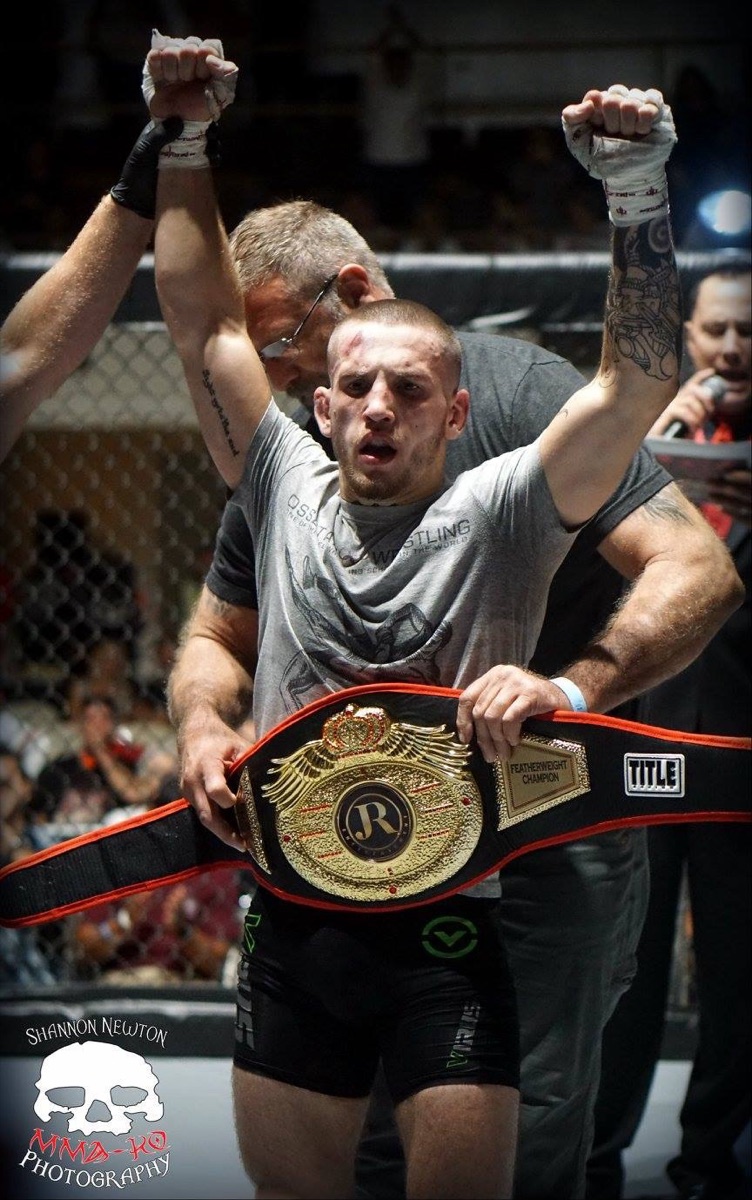 Coach David raising a championship belt in the cage