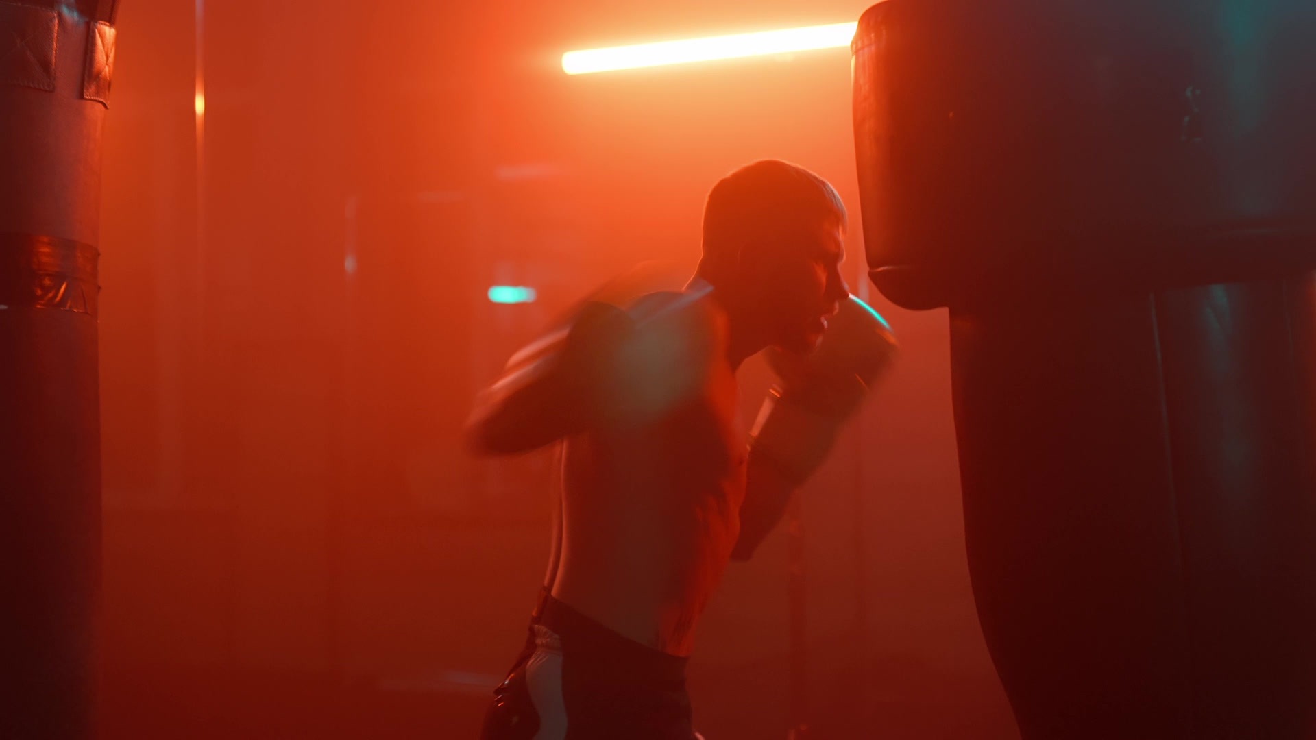 Fighter striking a heavy bag in moody red light