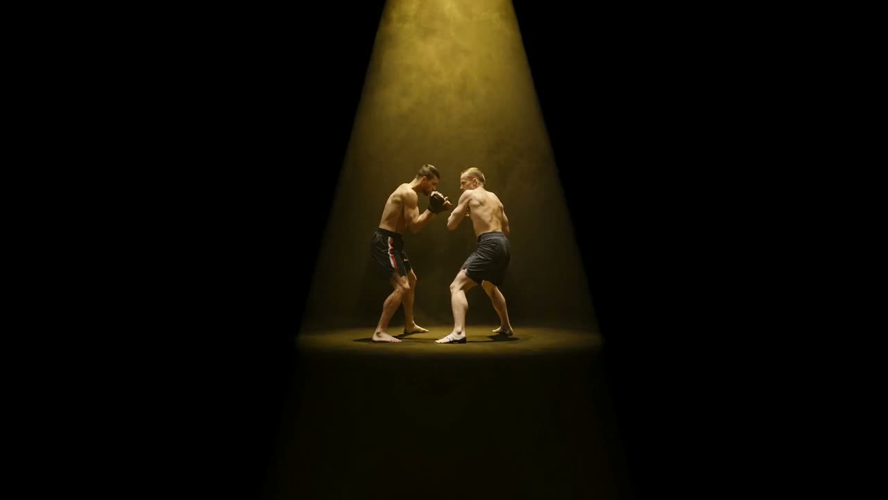 Two fighters sparring under a single golden spotlight in a dark arena